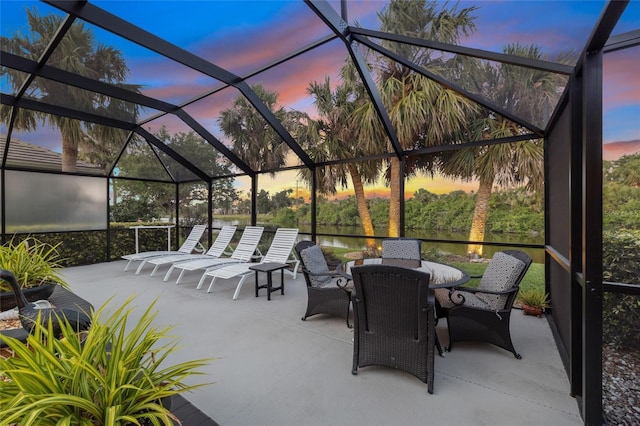 490 Pine Lily Way, Venice, FL 34293 - patio terrace at dusk with a water view, glass enclosure, and outdoor dining area