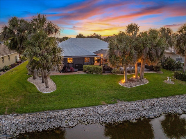490 Pine Lily Way, Venice, FL 34293 - rear view of house featuring a yard, a tile roof, a water view, and stucco siding