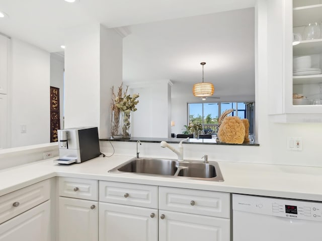 kitchen with white dishwasher, a sink, and white cabinets