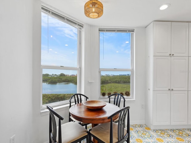 dining space with baseboards and a water view
