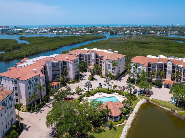 aerial view of apartment complex / building, a nearby body of water, and a pool area