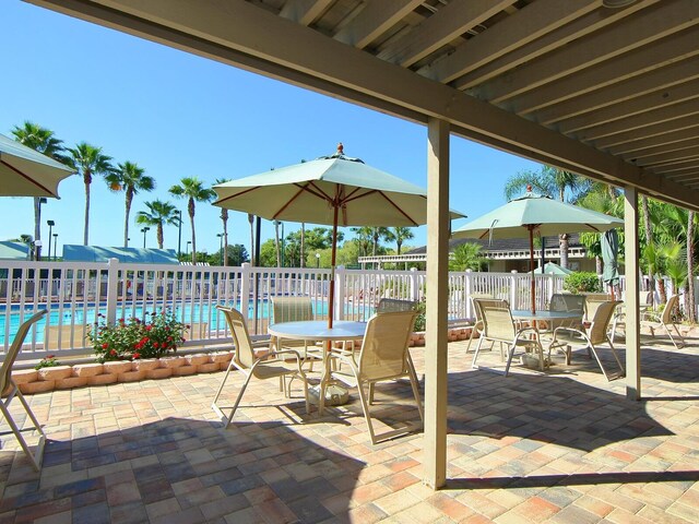 view of patio featuring outdoor dining space, fence, and a community pool