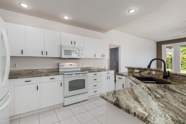 4063 Westbourne Cir, Sarasota, FL 34238 - kitchen with white appliances, a sink, dark stone counters, light tile patterned floors, and recessed lighting