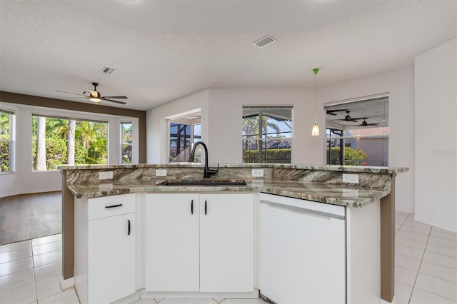 4063 Westbourne Cir, Sarasota, FL 34238 - kitchen featuring dishwasher, a sink, a ceiling fan, stone counters, and a textured ceiling