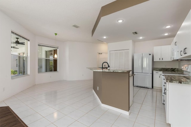 4063 Westbourne Cir, Sarasota, FL 34238 - kitchen with freestanding refrigerator, electric range, white cabinets, a center island with sink, and recessed lighting