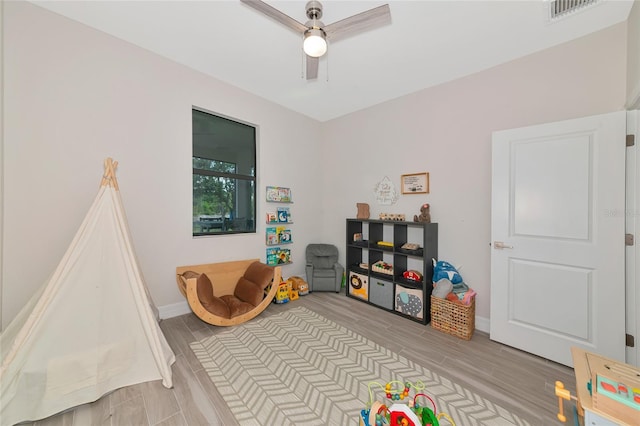 recreation room with a ceiling fan, light wood-style flooring, and baseboards