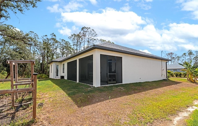 back of property featuring a sunroom and stucco siding