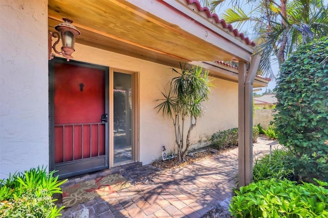 property entrance with stucco siding, a patio, and fence