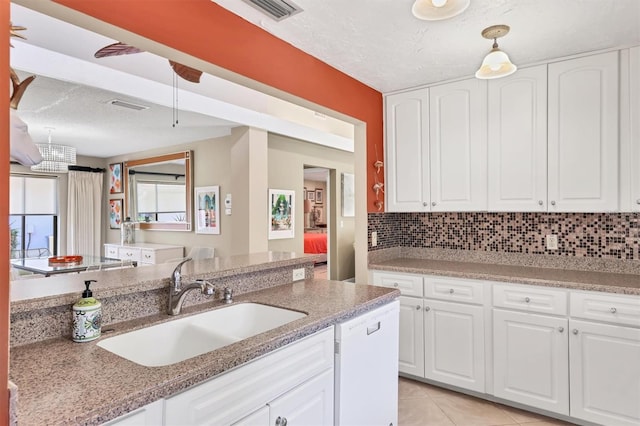 kitchen featuring a sink, decorative backsplash, white cabinets, and a textured ceiling