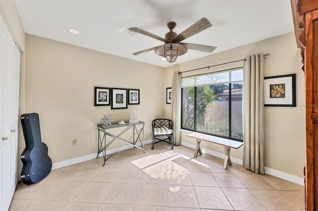 sitting room featuring a ceiling fan, baseboards, and light tile patterned floors