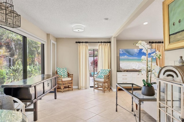 living area with healthy amount of natural light, light tile patterned floors, a textured ceiling, and baseboards