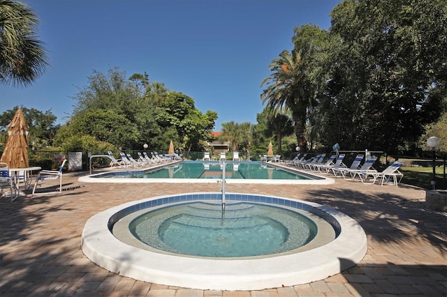 community pool with a community hot tub, a patio area, and fence