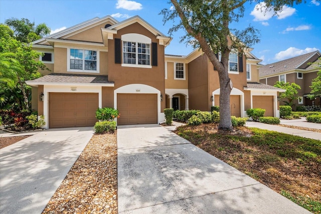 multi unit property with a garage, stucco siding, and driveway