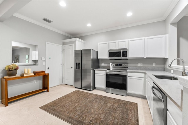 kitchen featuring appliances with stainless steel finishes, a sink, light tile patterned floors, white cabinetry, and crown molding