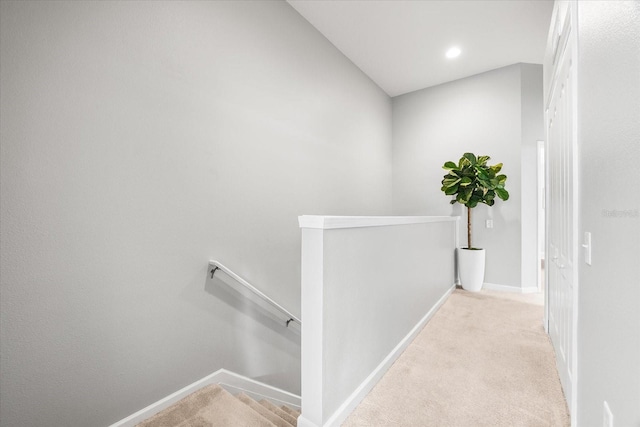 hallway featuring an upstairs landing, carpet flooring, and baseboards