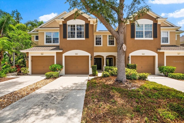 townhome / multi-family property featuring stucco siding, an attached garage, and driveway