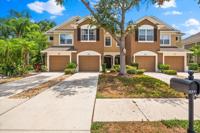 townhome / multi-family property with stucco siding, an attached garage, and driveway