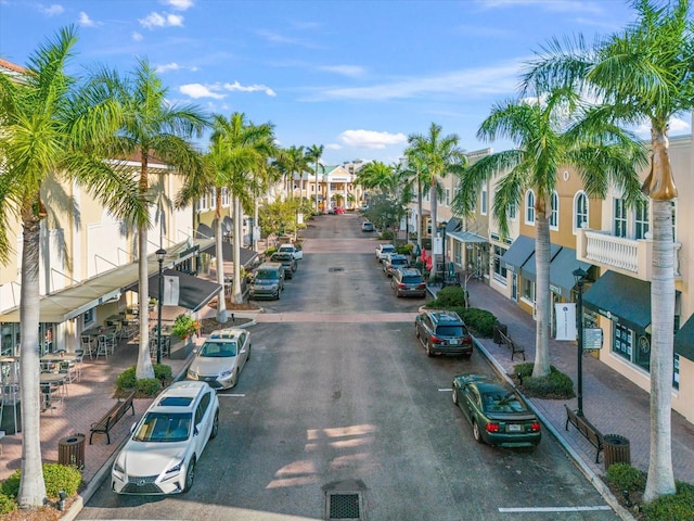 view of asphalt street featuring a residential view, street lighting, sidewalks, and curbs
