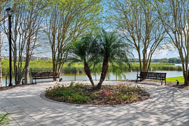 surrounding community with a water view and fence