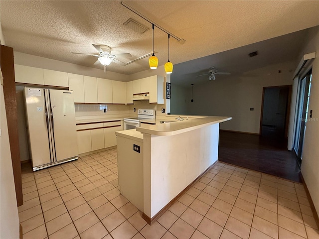 3957 Bearded Oaks Ct, Sarasota, FL 34232 - kitchen with white appliances, ceiling fan, under cabinet range hood, light tile patterned floors, and a peninsula