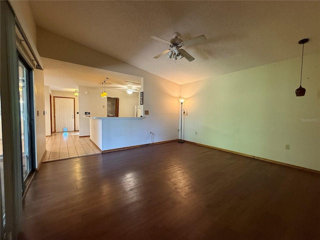 3957 Bearded Oaks Ct, Sarasota, FL 34232 - unfurnished living room featuring wood finished floors, a ceiling fan, lofted ceiling, a textured ceiling, and baseboards