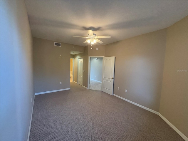 carpeted spare room featuring baseboards, a ceiling fan, and visible vents