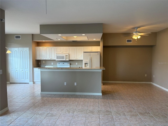 kitchen featuring white appliances, baseboards, visible vents, white cabinets, and a kitchen island