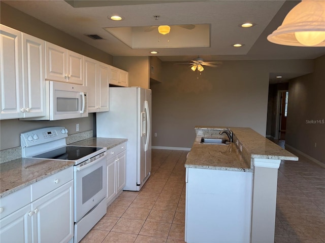 kitchen with light tile patterned floors, a sink, a tray ceiling, baseboards, and white appliances
