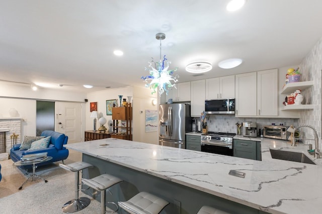 2207 Hickory Ave, Sarasota, FL 34234 - kitchen featuring appliances with stainless steel finishes, a sink, light stone countertops, and a peninsula