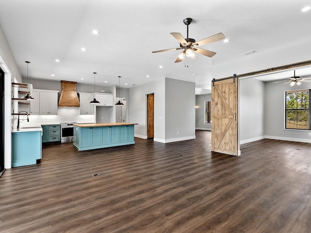 unfurnished living room featuring dark wood-style flooring, a barn door, a ceiling fan, and recessed lighting