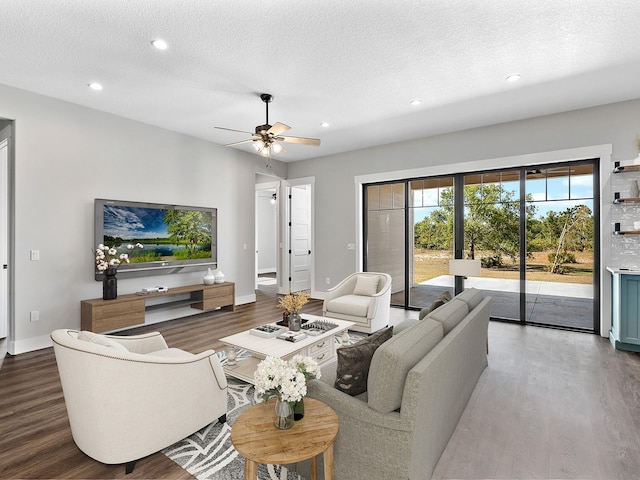 living room featuring baseboards, a textured ceiling, and wood finished floors