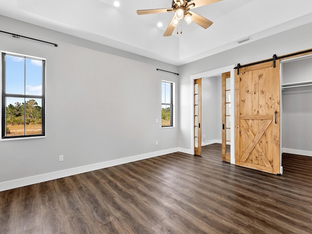 unfurnished bedroom with a barn door, recessed lighting, baseboards, dark wood-style flooring, and visible vents