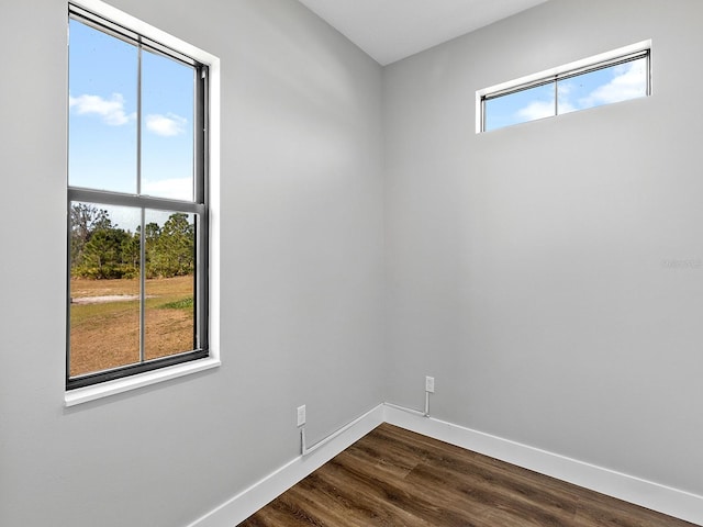 unfurnished room featuring baseboards and dark wood-style floors