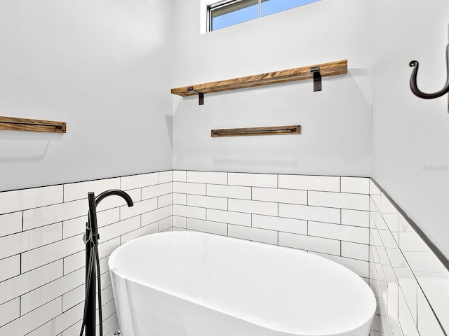 full bathroom featuring a soaking tub, tile walls, and a wainscoted wall