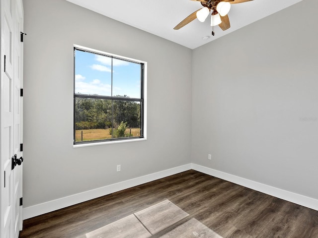 empty room featuring a ceiling fan, baseboards, and dark wood finished floors