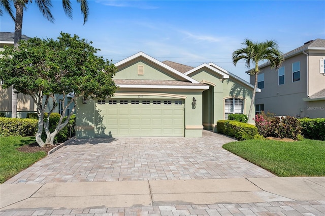 view of front of home with stucco siding, an attached garage, decorative driveway, and a front yard