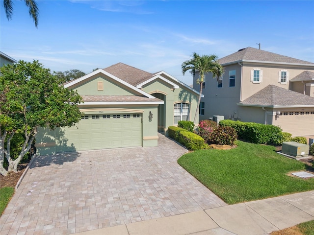 view of front of property with stucco siding, decorative driveway, an attached garage, and a front yard