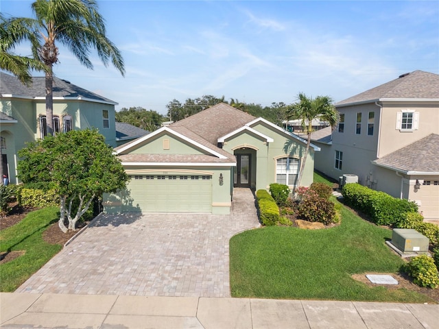 view of front of house featuring decorative driveway, a garage, a front yard, stucco siding, and central AC