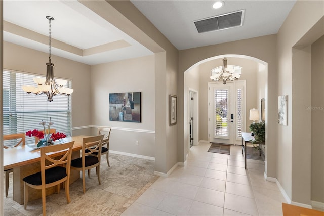foyer featuring a chandelier, arched walkways, baseboards, and light tile patterned floors