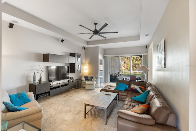 living room with a ceiling fan and a raised ceiling
