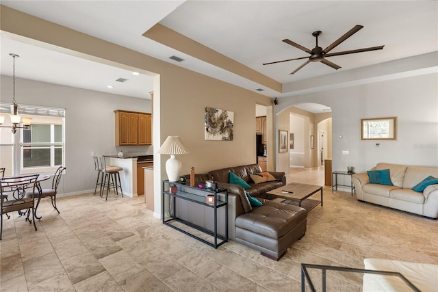 living room with arched walkways, a ceiling fan, a chandelier, and baseboards