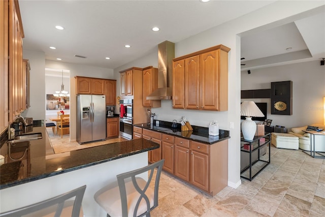 kitchen featuring appliances with stainless steel finishes, wall chimney exhaust hood, a sink, a peninsula, and recessed lighting