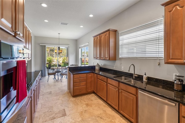 kitchen with appliances with stainless steel finishes, a sink, recessed lighting, brown cabinets, and a peninsula