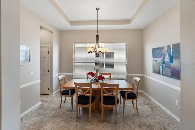 dining area featuring a chandelier, a tray ceiling, and baseboards