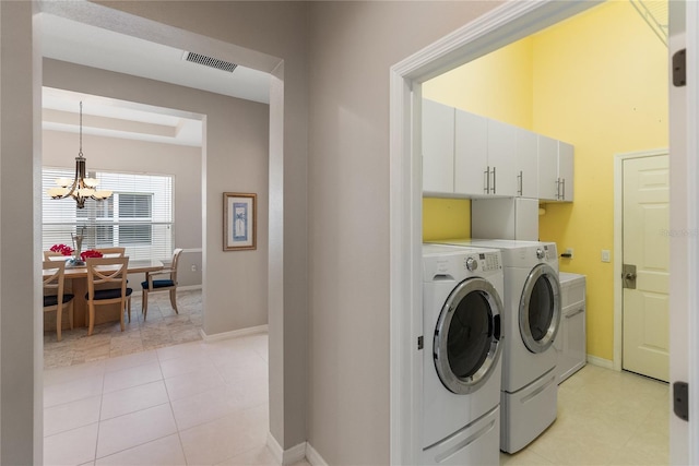 clothes washing area featuring independent washer and dryer, cabinet space, a chandelier, and baseboards