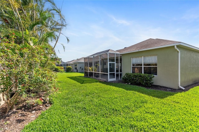 back of property featuring stucco siding, a lawn, and roof with shingles