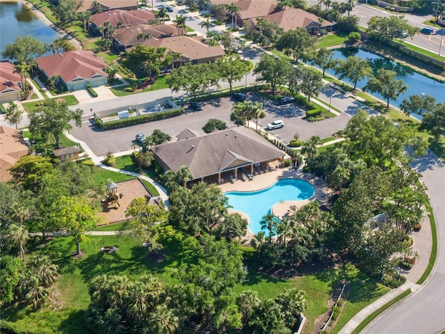 aerial overview of property's location featuring a large body of water, a pool area, and nearby suburban area