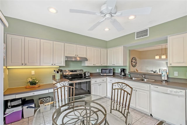 1159 Lake House Cir Unit C120, Sarasota, FL 34242 - kitchen featuring stainless steel appliances, a sink, under cabinet range hood, light tile patterned floors, and white cabinetry