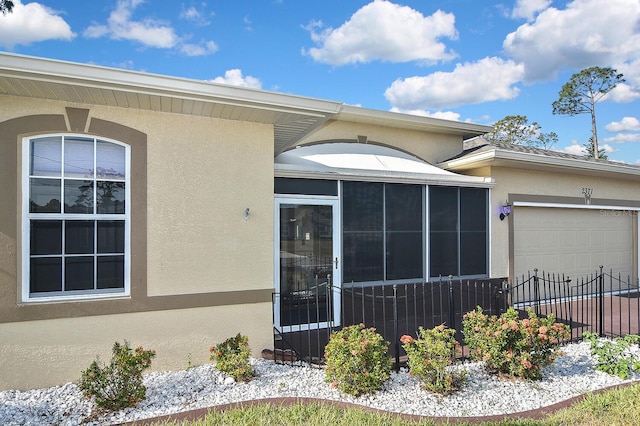 property entrance with stucco siding, an attached garage, and fence