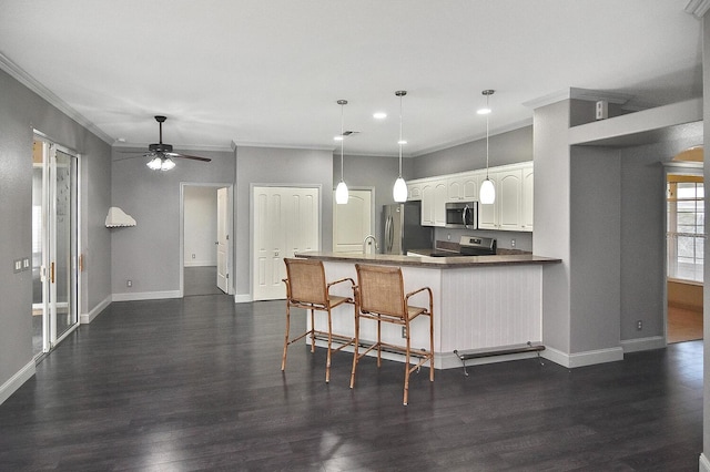 kitchen featuring stainless steel appliances, crown molding, baseboards, ceiling fan, and dark wood-style floors